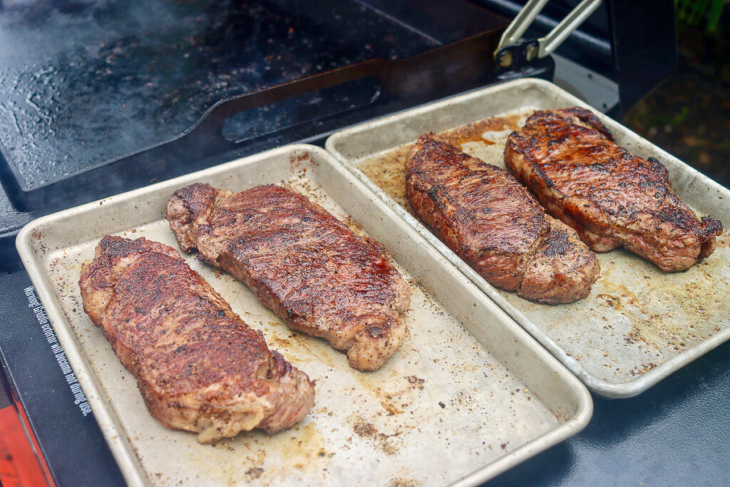 four steaks resting on a metal tray