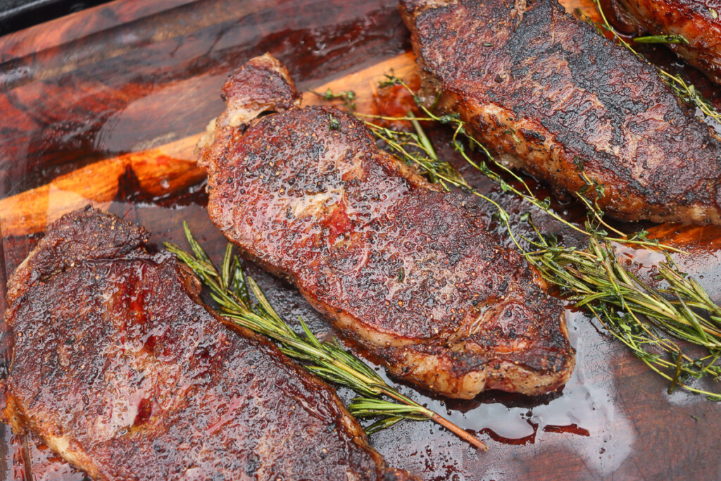 cooked steaks resting on a wooden board