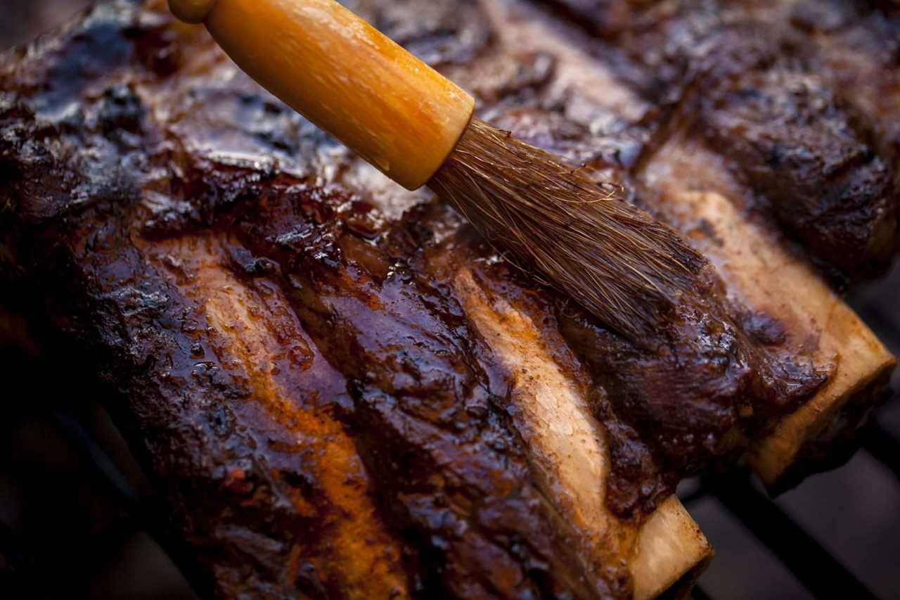 smoked beef ribs being brushed with BBQ sauce