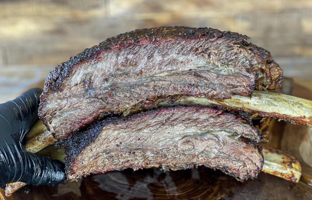 smoked beef ribs stacked on a wood cutting board