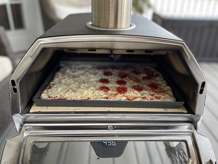 Ooni Karu 16 with an open glass door and pizza inside the cooking chamber