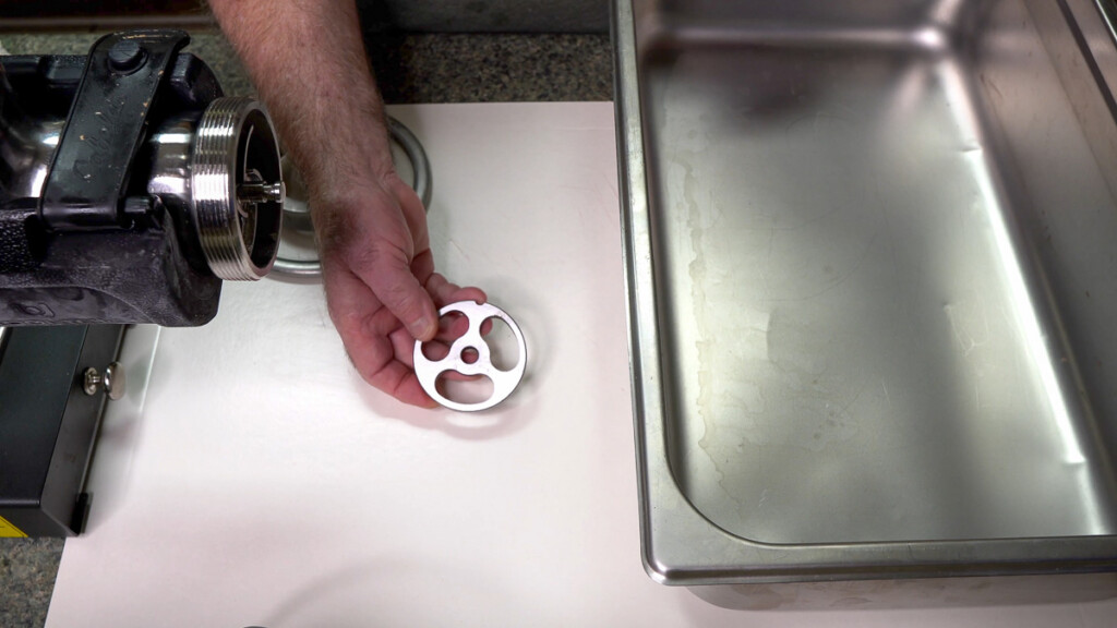 a hand holding a kidney plate for grinding