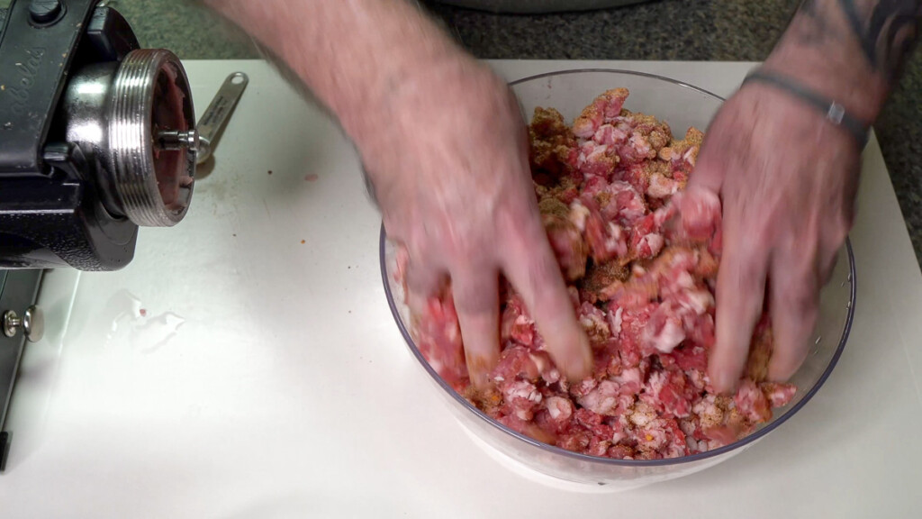 a hand mixing raw ground meat