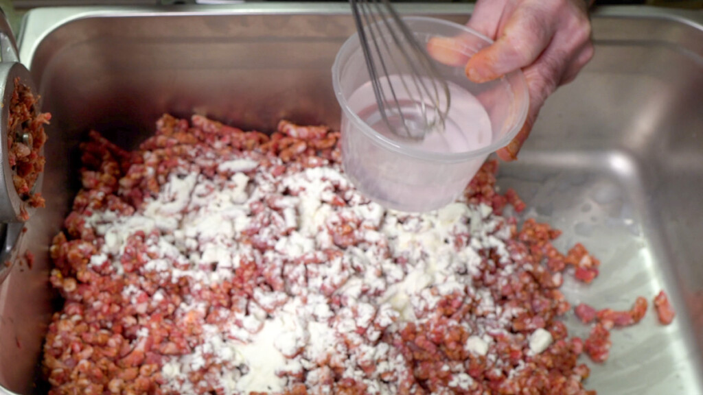 a jug of water and sodium nitrate being stirred above the ground raw meat