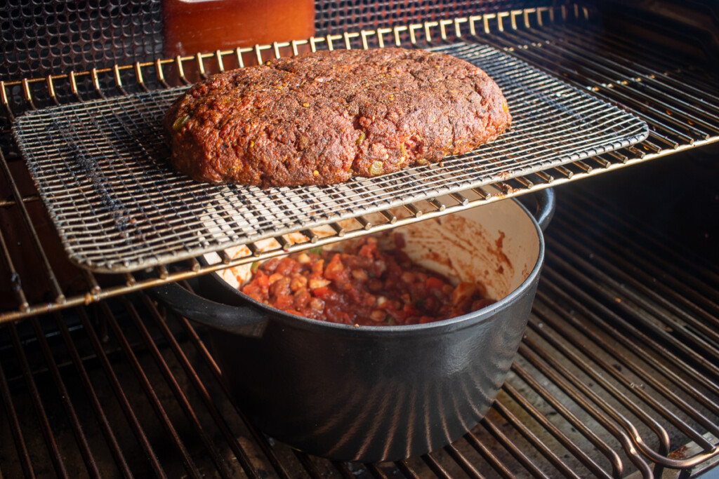 beef roll sitting over a dutch oven in the smoker