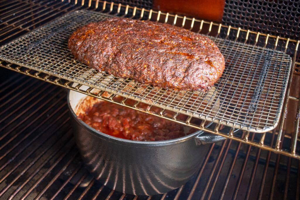 meat over a dutch oven in the smoker