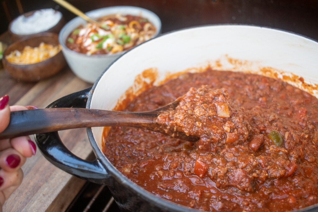 a pot of over the top chili with a spoon in it