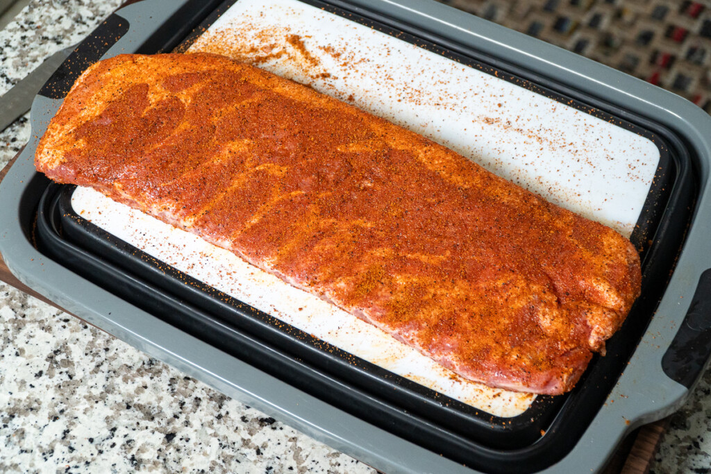 a raw rack of ribs seasoned on a white board