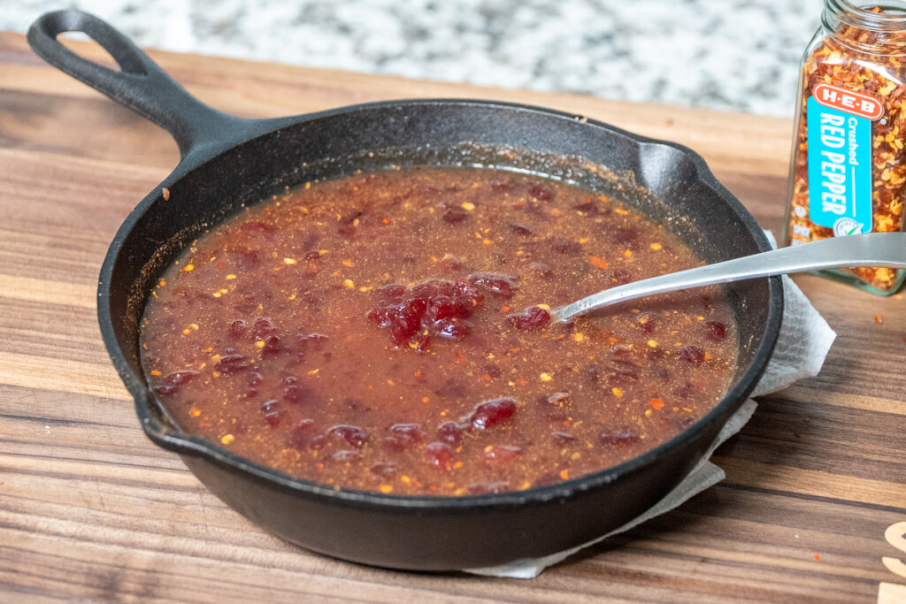 unsmoked cranberry glaze in a cast iron skillet with a spoon in it