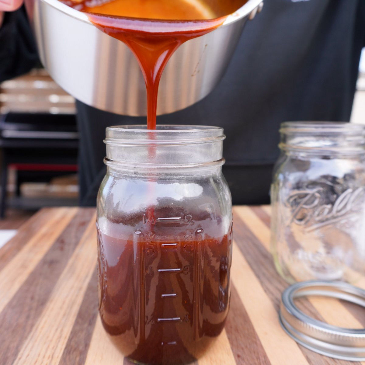 Pouring sauce into a mason jar.