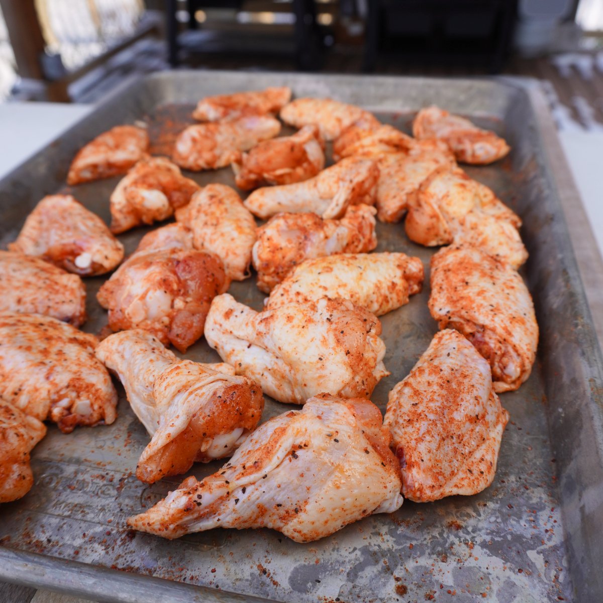 Seasoned detached chicken wings on a metal tray.