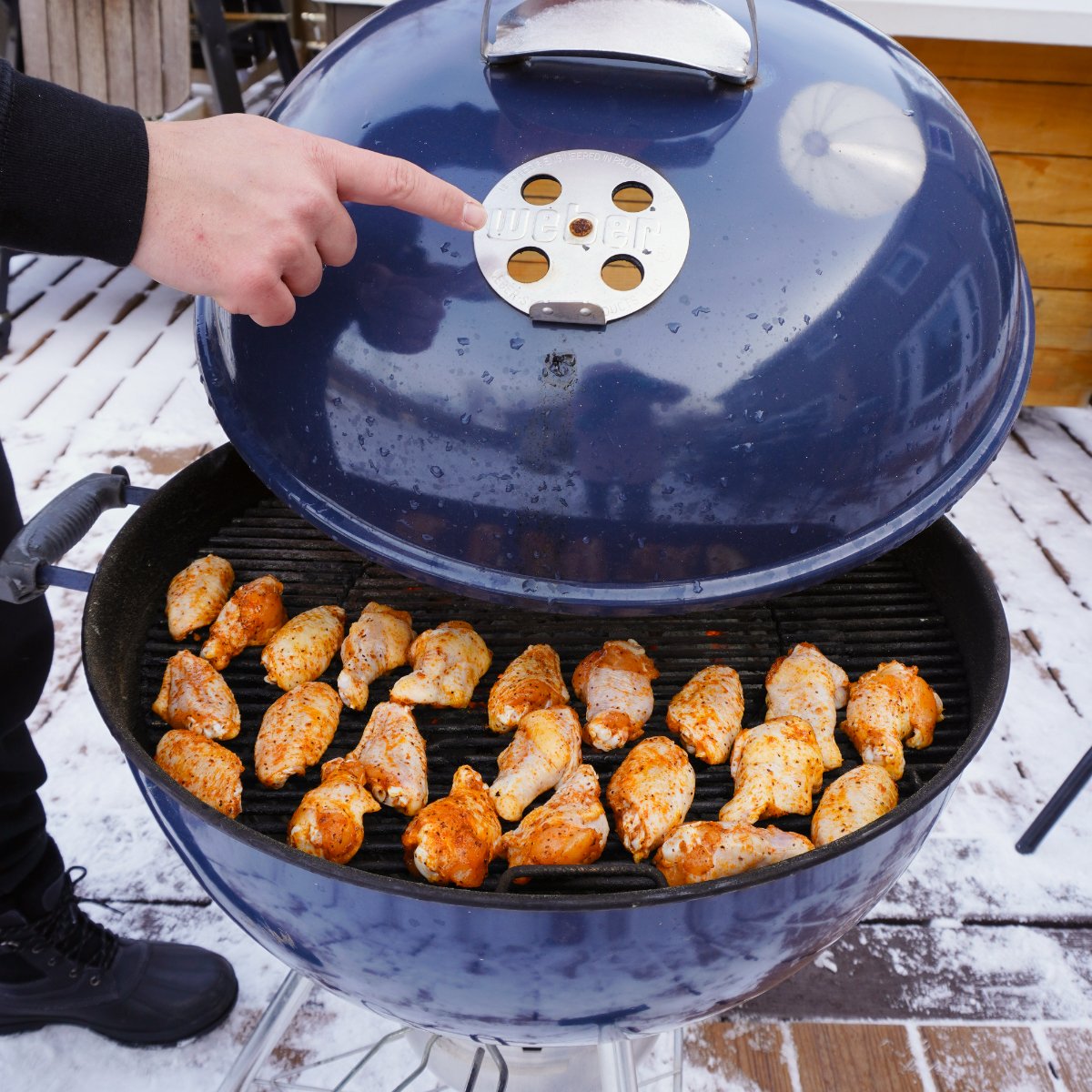 Grill lid with top vents directly above the seasoned wings on the grill grates.