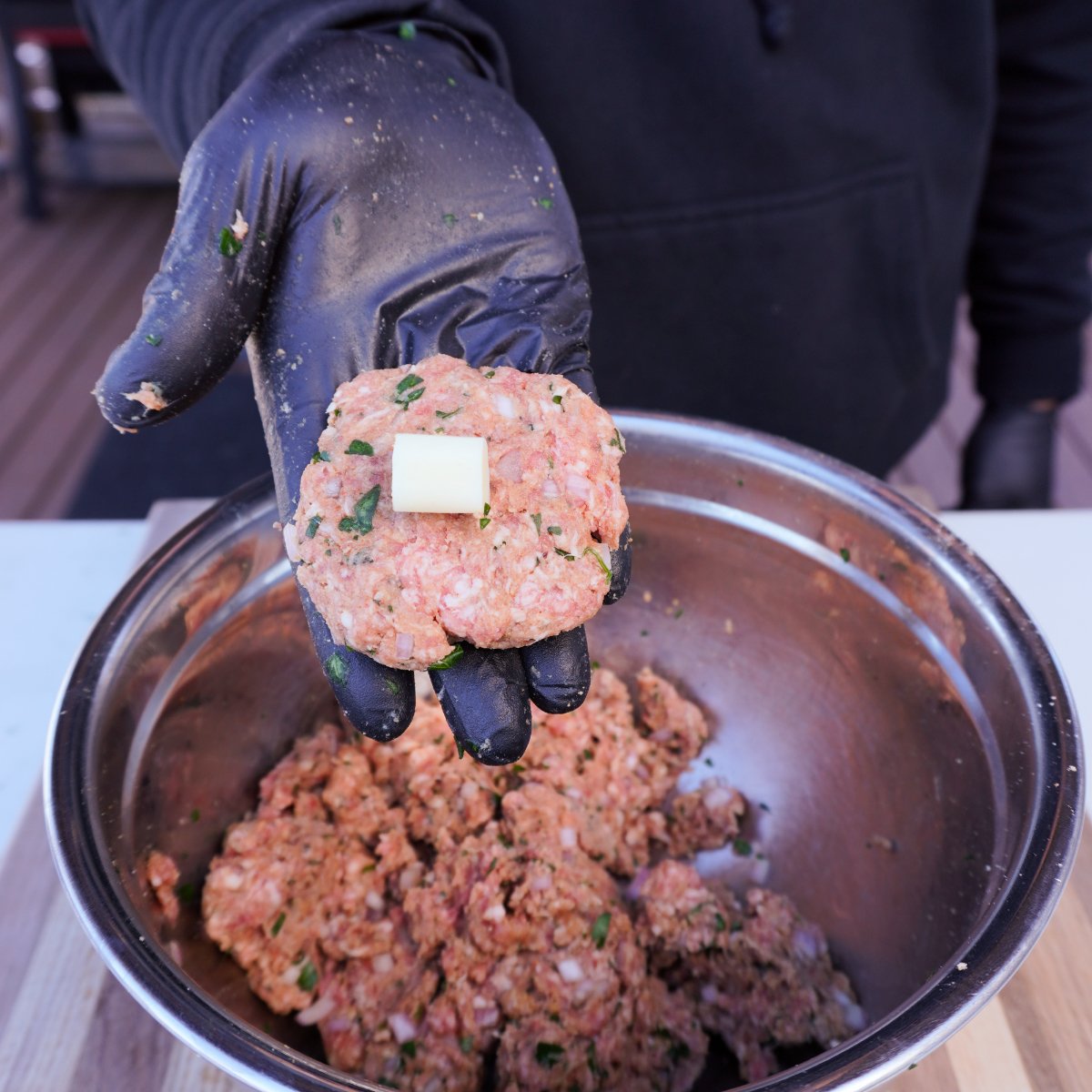 Piece of mozzarella cheese in the middle of a flat meatball mix patty.