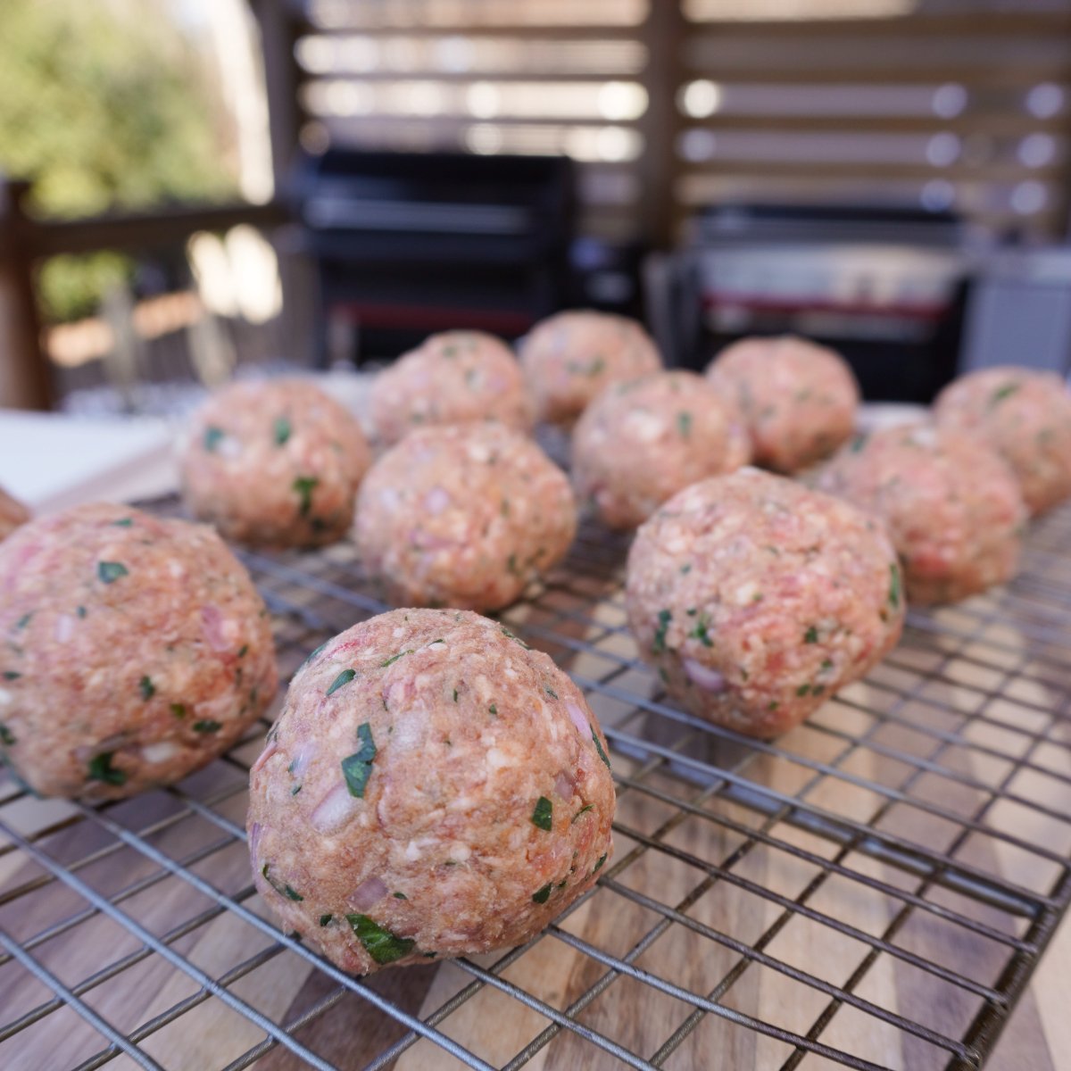 round formed raw meatballs on a wire rack.