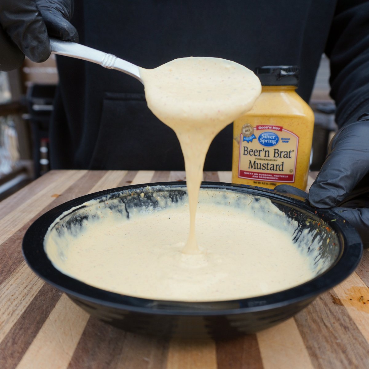 Creamy mustard sauce pouring from a spoon.