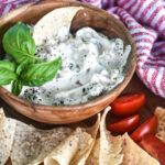 blt dip in wooden bowl on platter with red and white dish towel and tortilla chips and pork rinds for low carb eaters