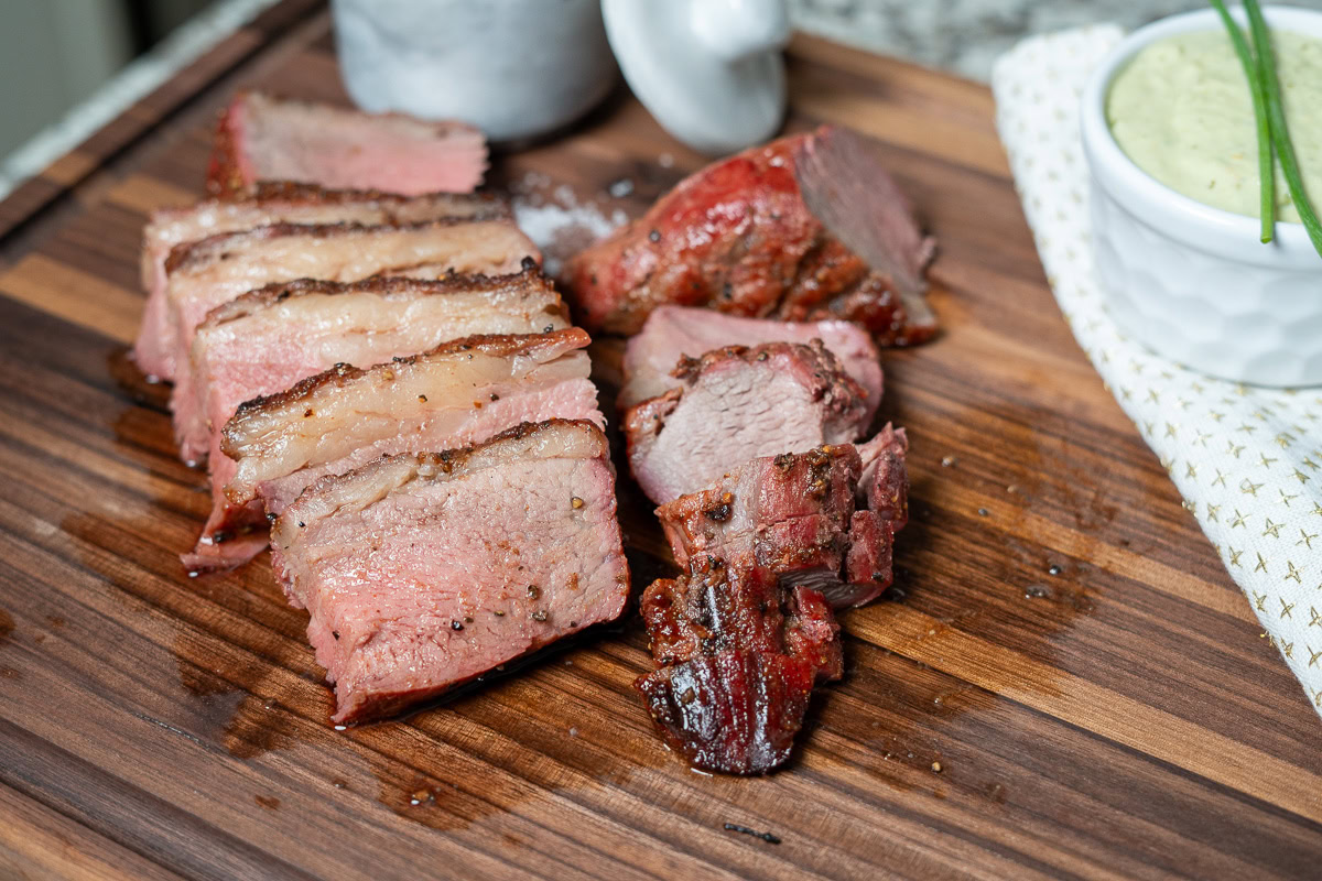 cooked and sliced tri-tip on a wooden board