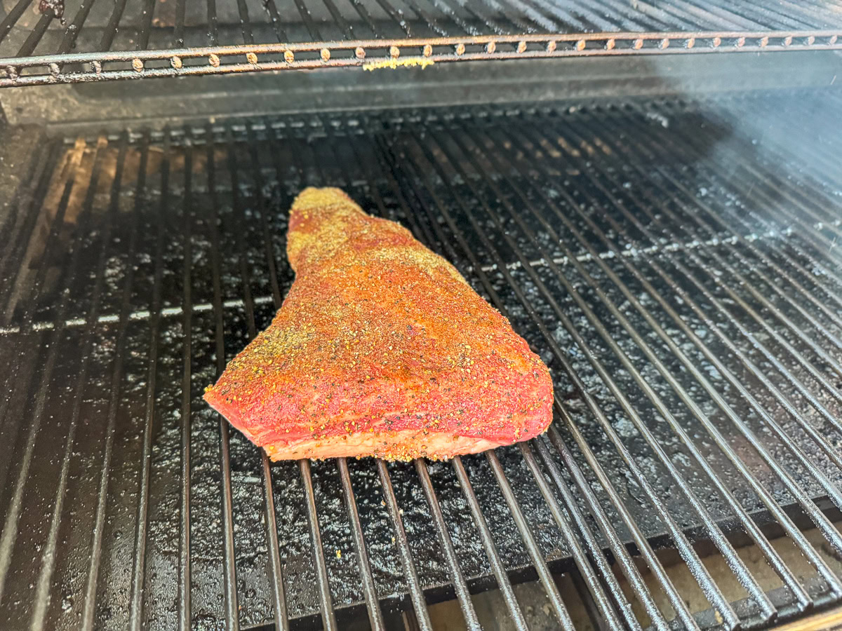 a raw piece of seasoned tri-tip on the smoker