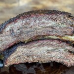 smoked beef ribs stacked on a wood cutting board