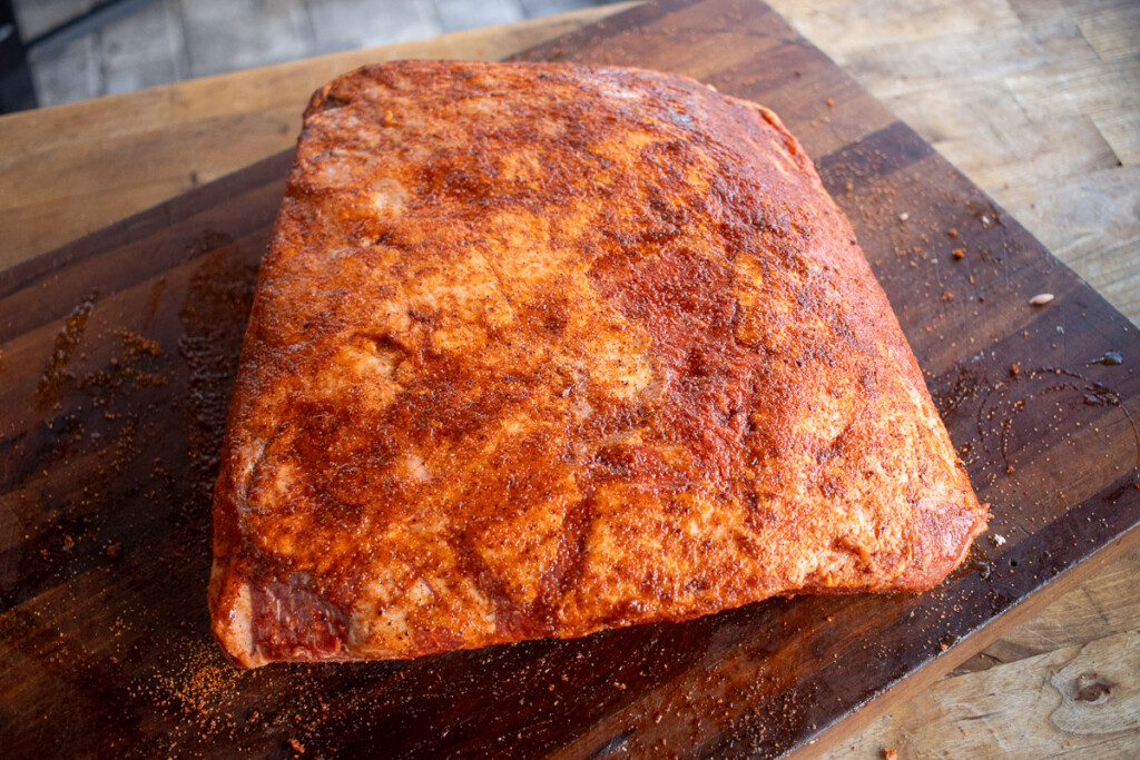 a raw beef rib with seasoning spread all over it