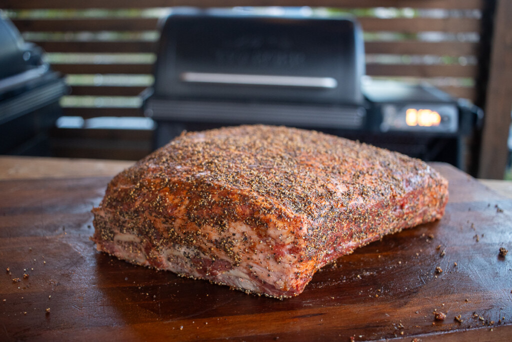 a raw piece of beef rib with seasoning and cracked pepper on it