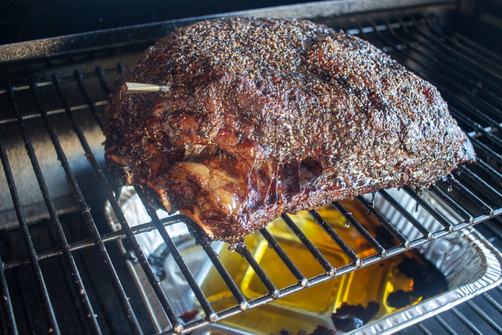 a cooked prime rib in the smoker with a foil tray underneath