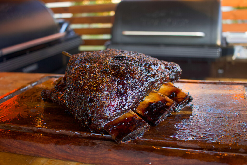 a rack of cooked prime ribs resting on a wooden chopping board