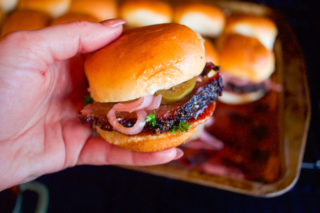 a hand holding a prime rib slider