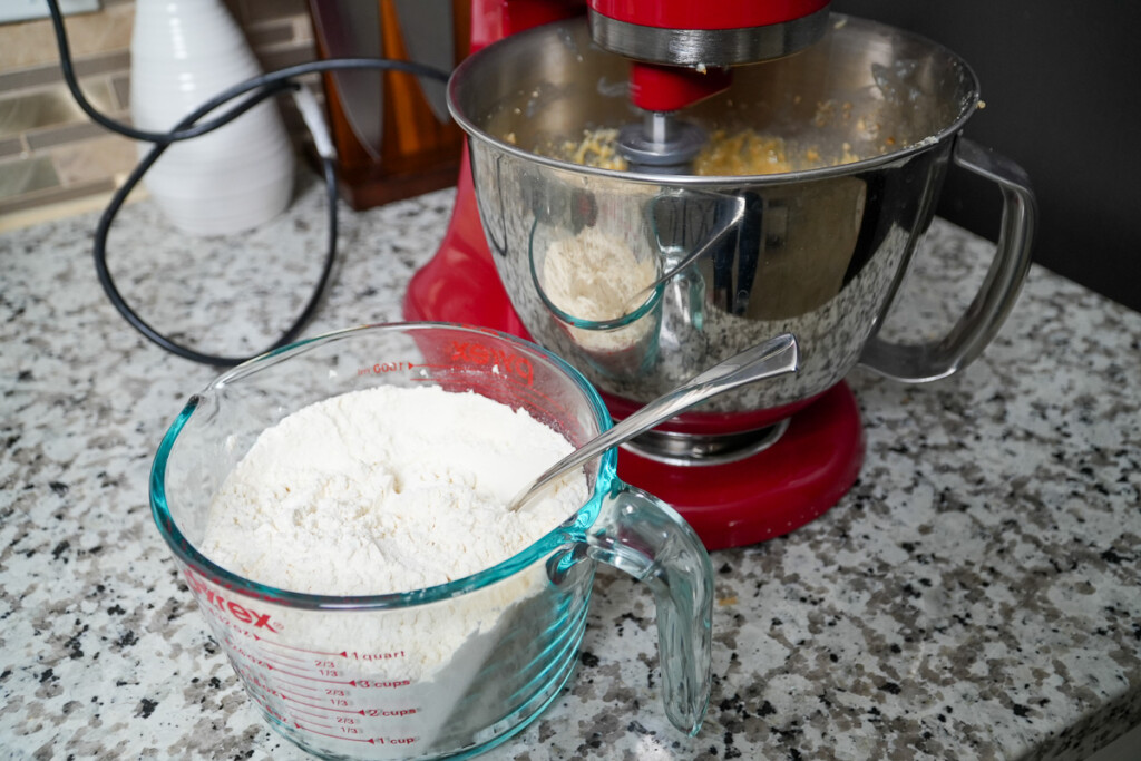 a measuring jug of flour besides a red stand mixer