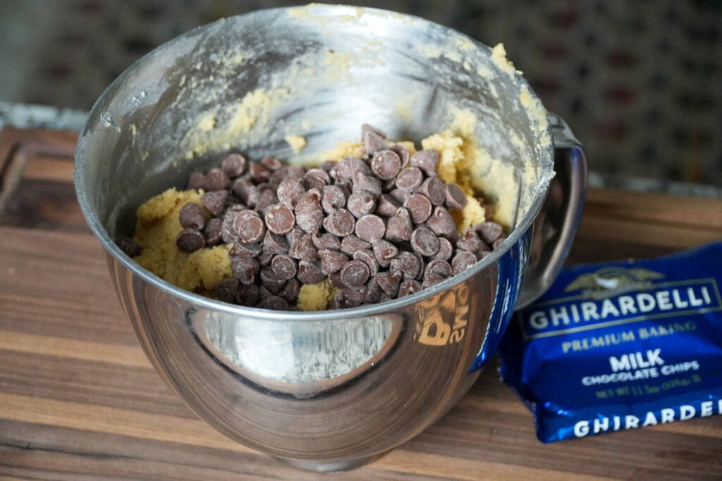 a mixing bowl with cookie dough and chocolate chips in it