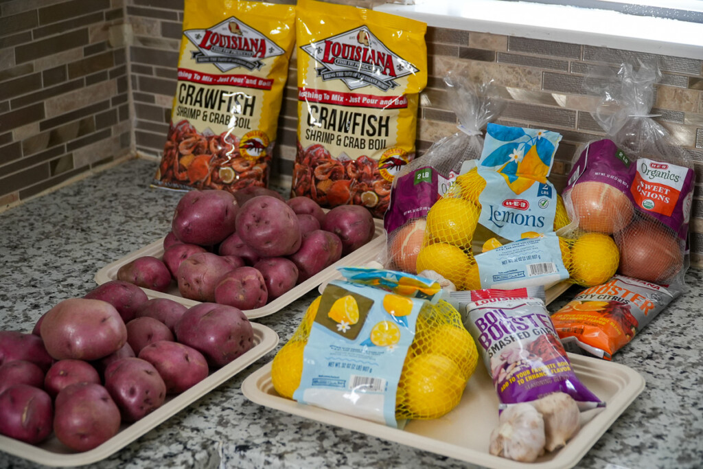 A countertop with red potatoes, bags of lemons, sweet onions, garlic, and Louisiana Crawfish & Crab Boil seasoning, all prepped for a traditional Cajun crawfish boil.