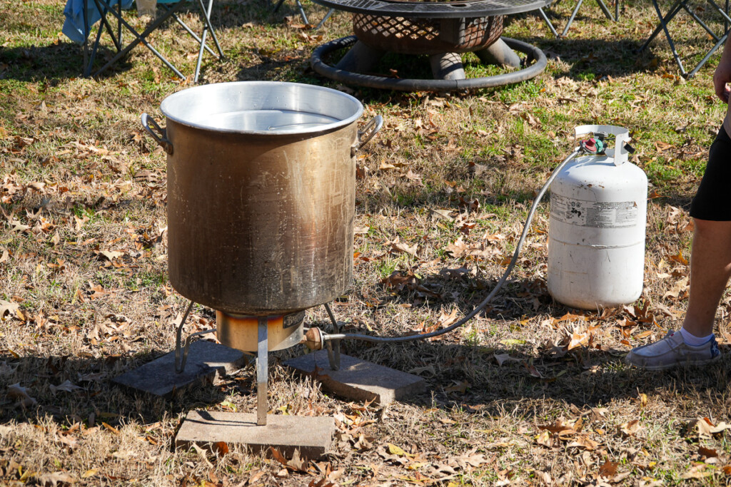 propane burner with a stockpot sitting on it on a lawn