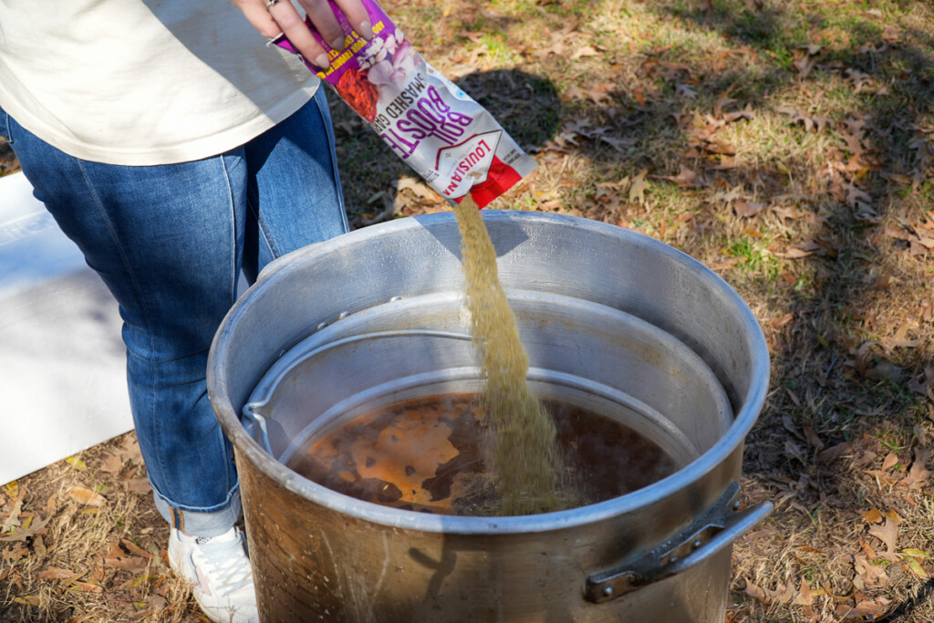 a bag of seasoning being added to a stockpot of water