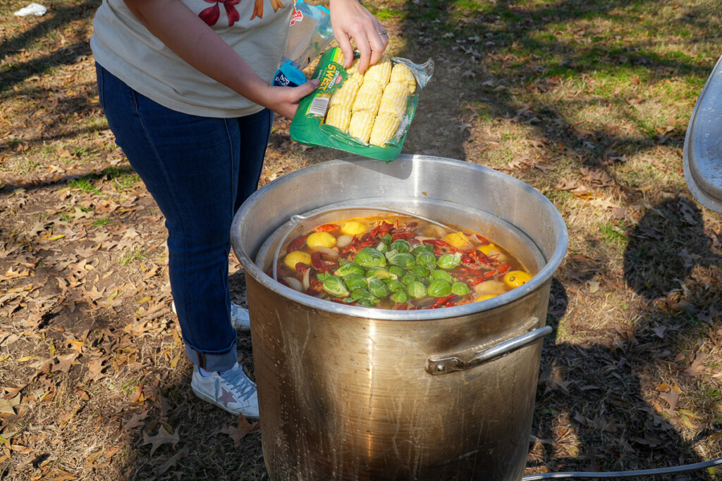 a women adding veges to a boiling stockpot