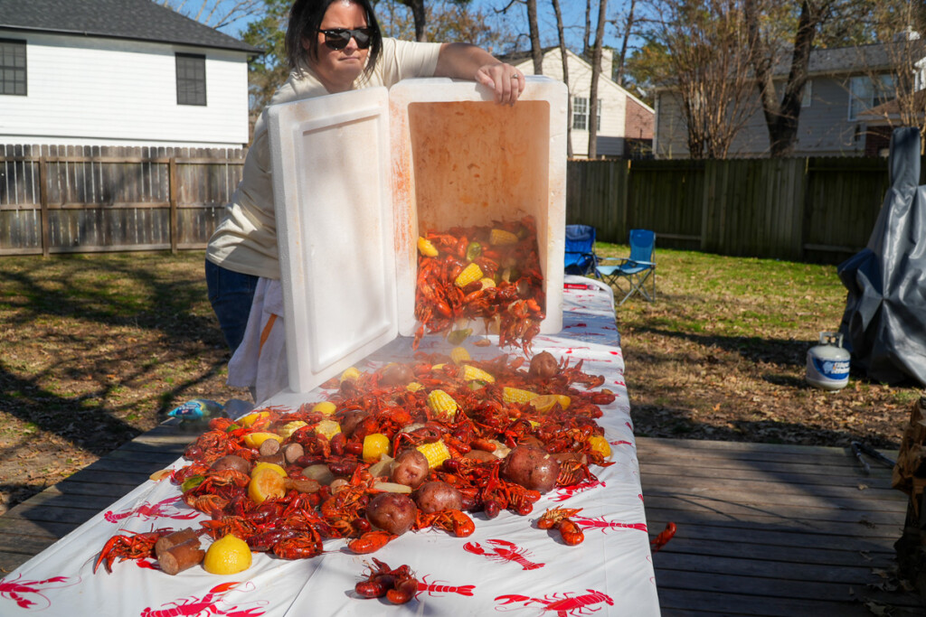 a women pouring the contents of the crawfish cooler onto a table