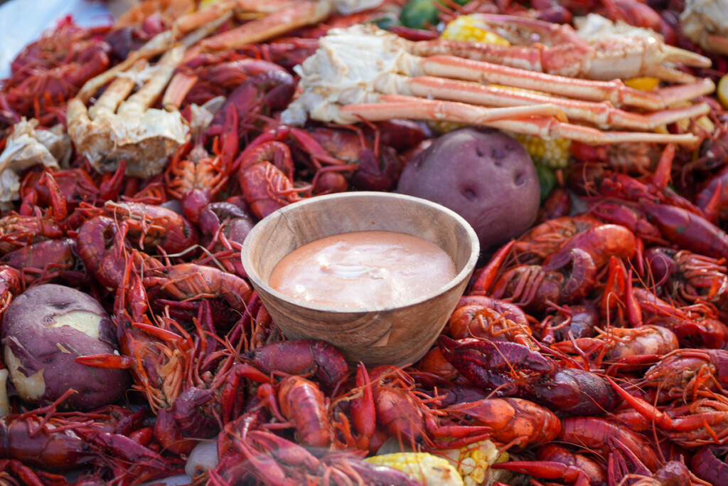 a white bowl of dip in the middle of the crawfish boil