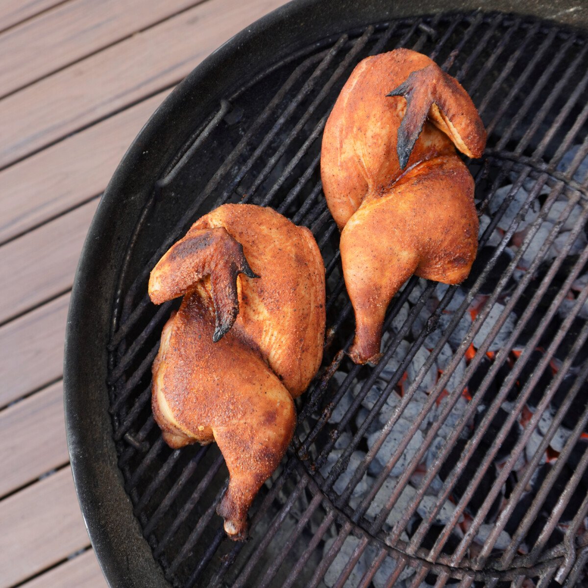 seasoned chicken halves on the direct side of a charcoal grill.