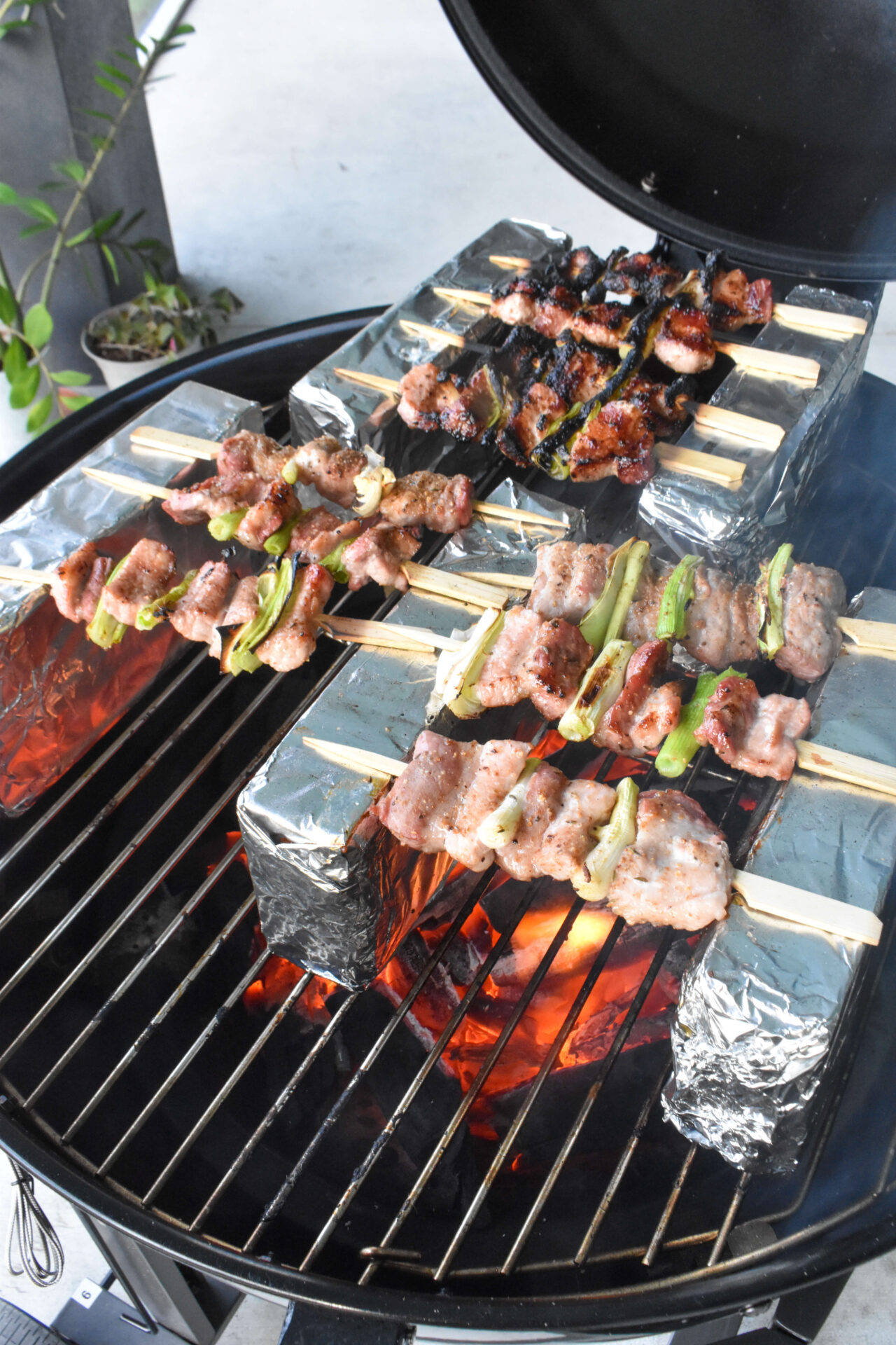 Pork Belly Yakitori Skewers cooking on a charcoal grill.