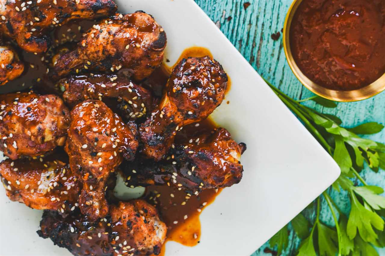 A plate of Gochujang chicken wings next to a bowl of extra sauce. 