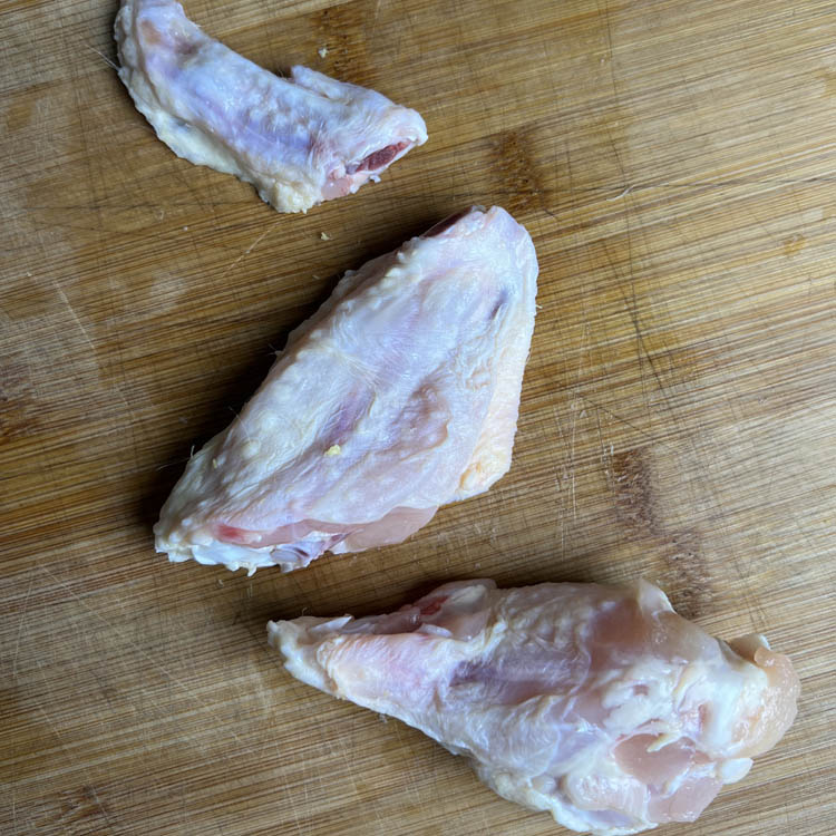 raw wing cut into 3 parts on wooden chopping board