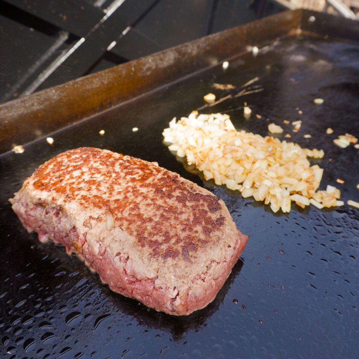 beef block and diced onions on the griddle.