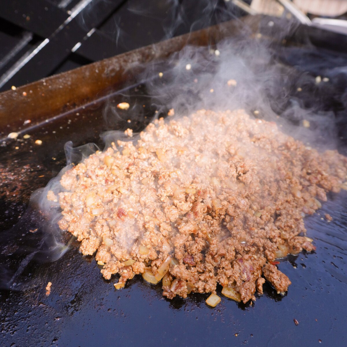 beef and onion mixed together on the grill.