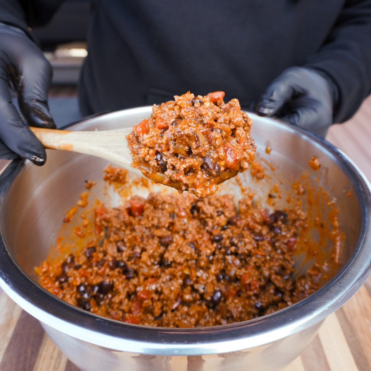 beef enchilada filing scooped up on a wooden spoon.