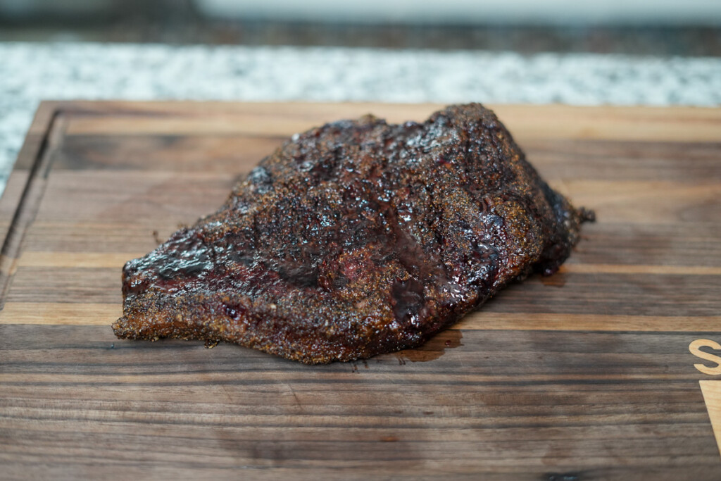 a cooked brisket point resting on a wooden chopping board