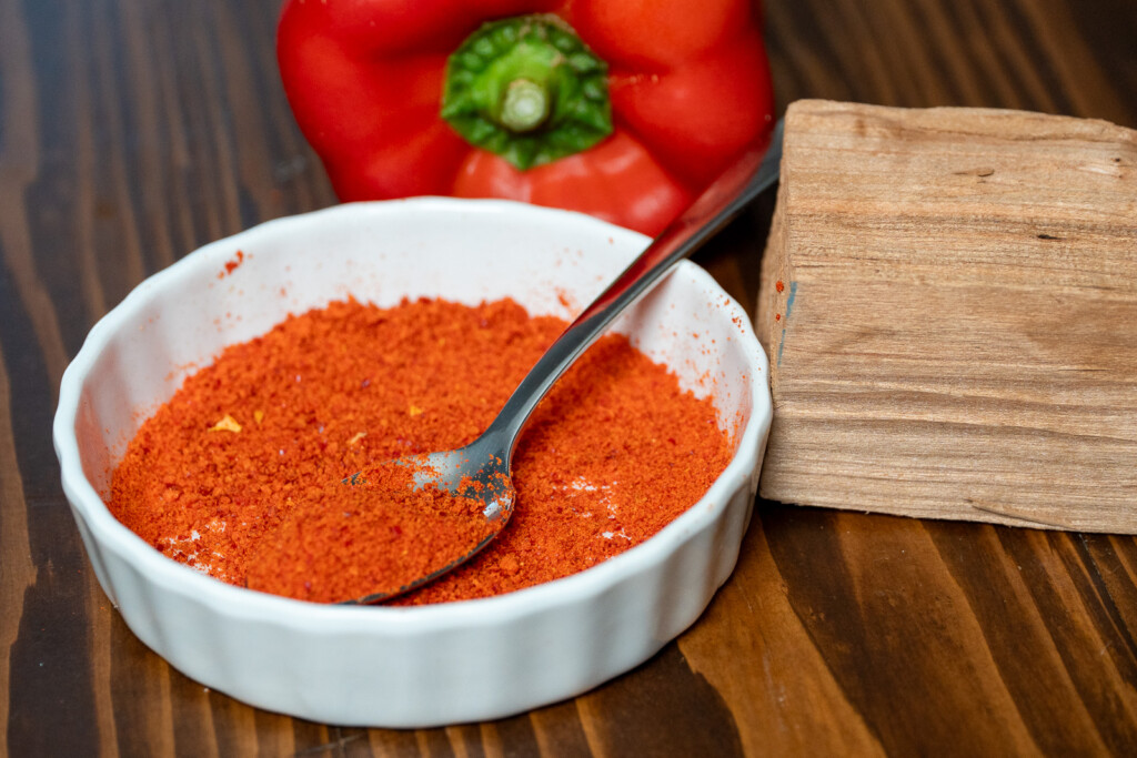 a white bowl with a spoon and smoked paprika in it