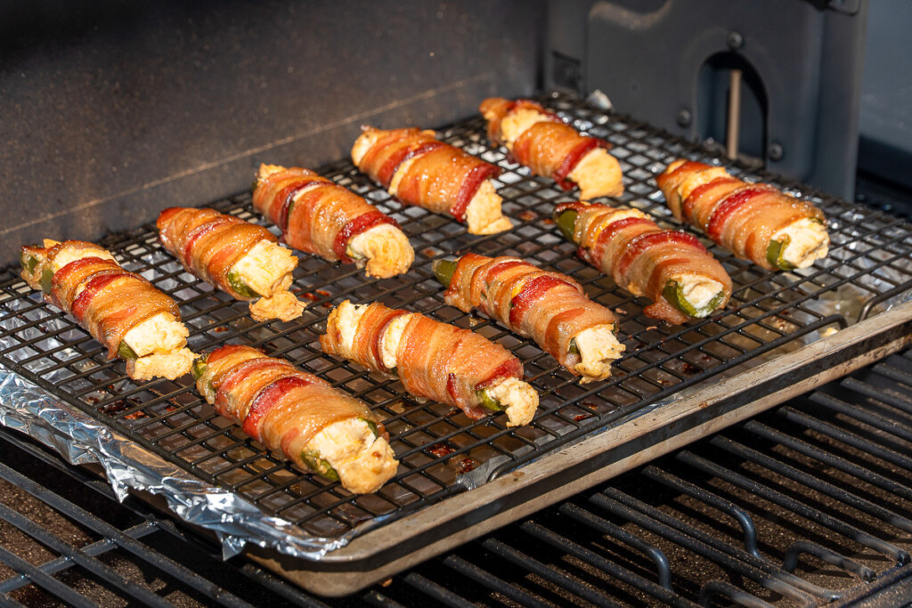 Tray of bacon-wrapped jalapeño poppers cooking inside the Traeger Woodridge Pro pellet grill.