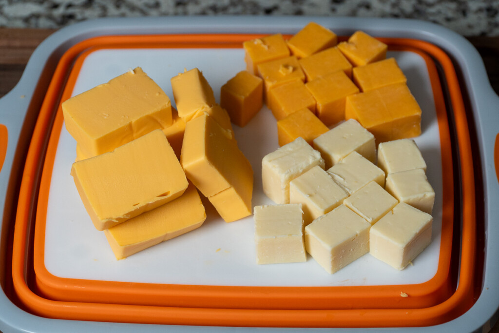 an array of cubed up cheese on a white cutting board