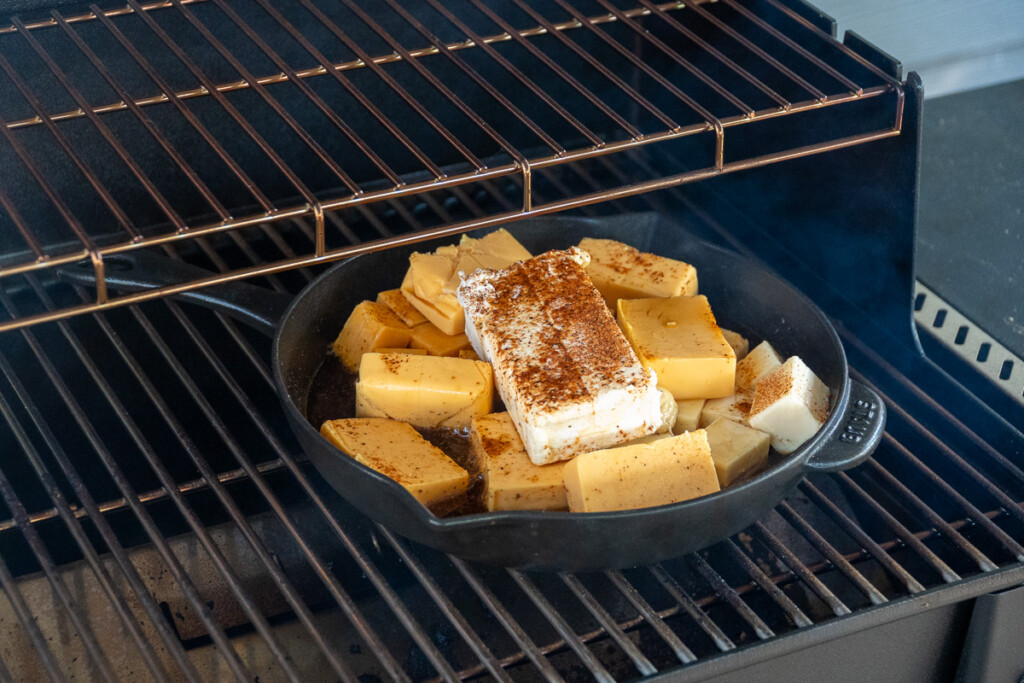a skillet on the smoker full of cubed seasoned cheese