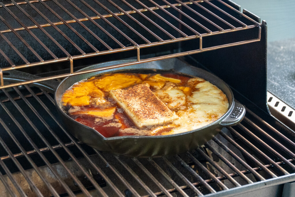 a skillet in the smoker with a lot of cheese in the melting process