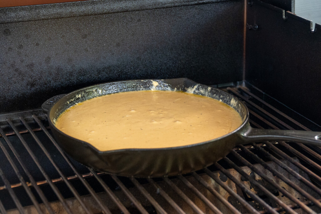 a skillet on the smoker filled with melted cheese